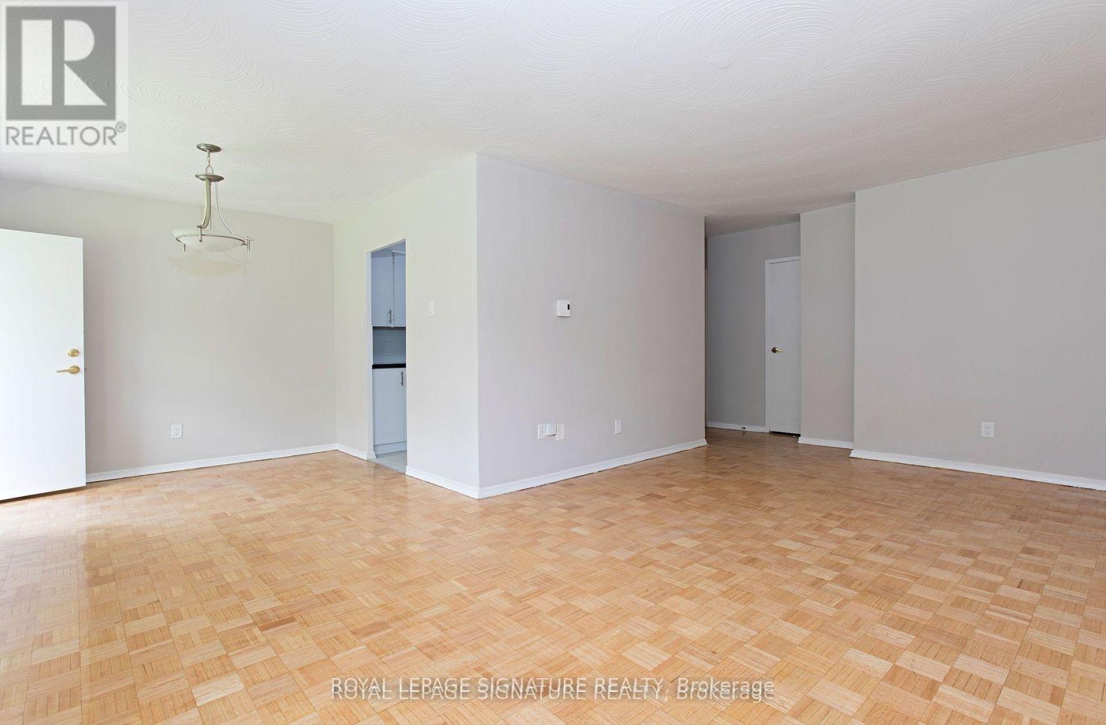 A large empty room with wooden flooring and white walls.