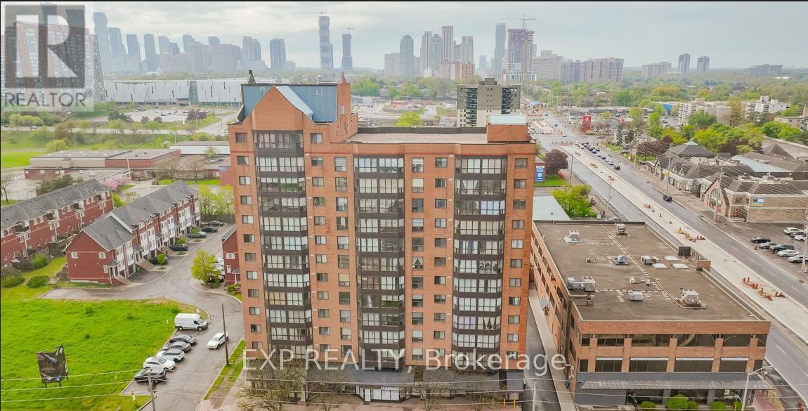A tall brick building with a green roof is in the foreground with a city skyline in the background.