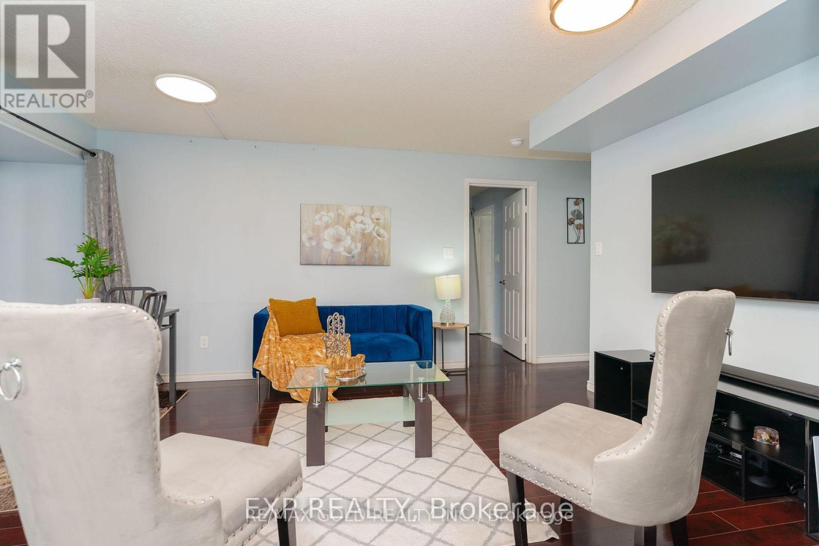 A living room with a white sofa, a white chair, and a glass coffee table.