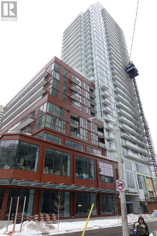 A crane is lifting a platform to the top of a tall building.