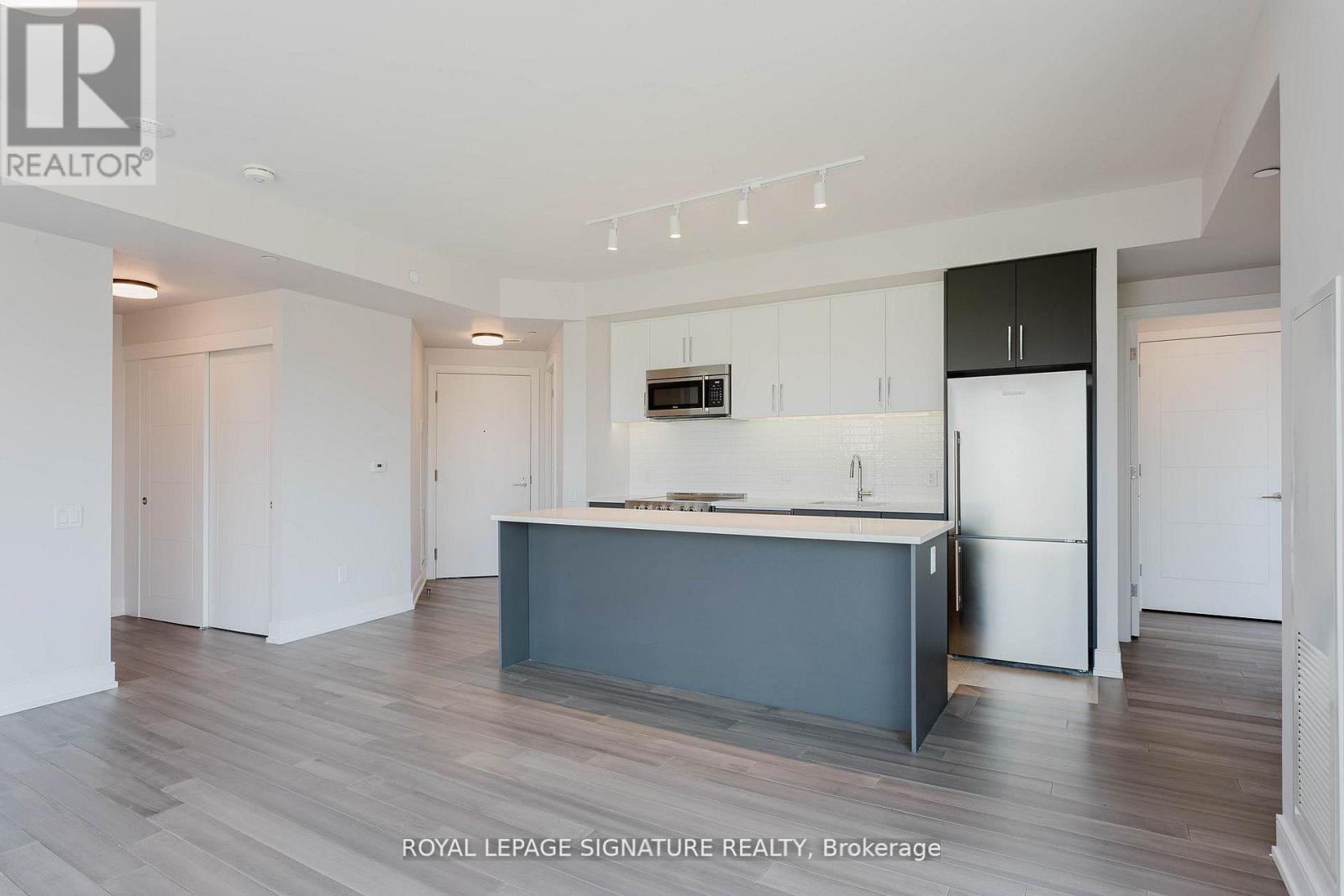 A modern kitchen with a dark grey island and white cabinets.