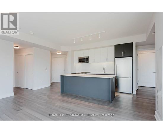 A modern kitchen with a dark grey island and white cabinets.