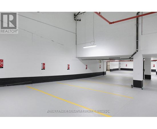 A spacious garage with yellow lines on the floor and red pipes on the ceiling.