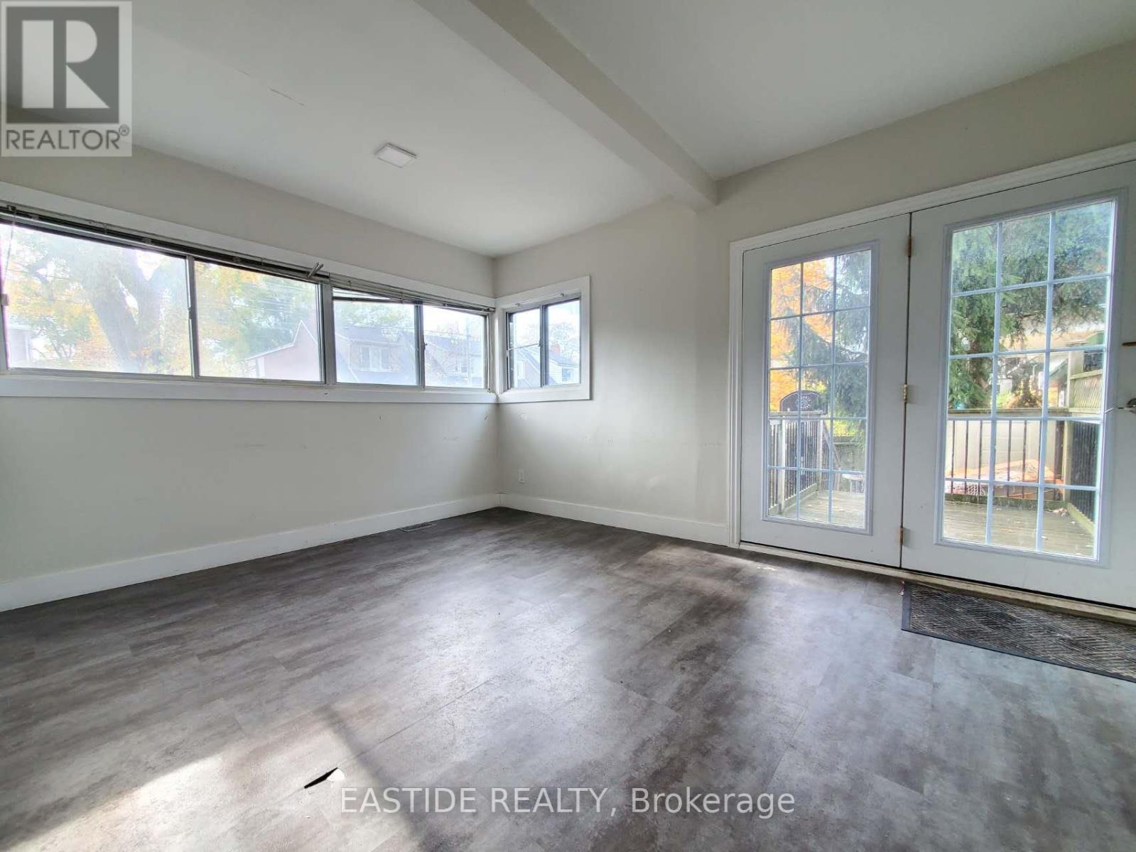 A sunny room with a slanted ceiling and a door leading to a balcony.