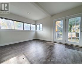 A sunny room with a slanted ceiling and a door leading to a balcony.