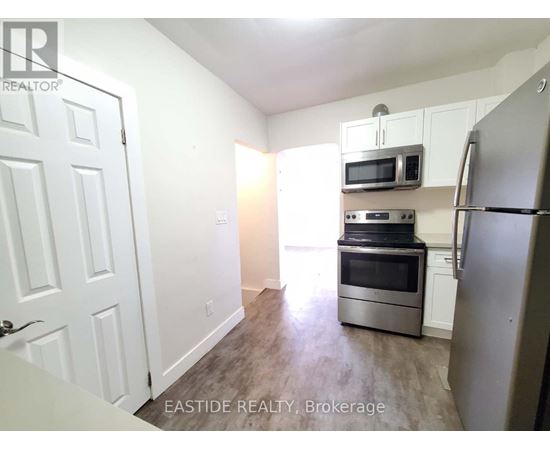 A kitchen with a refrigerator, microwave, and oven.