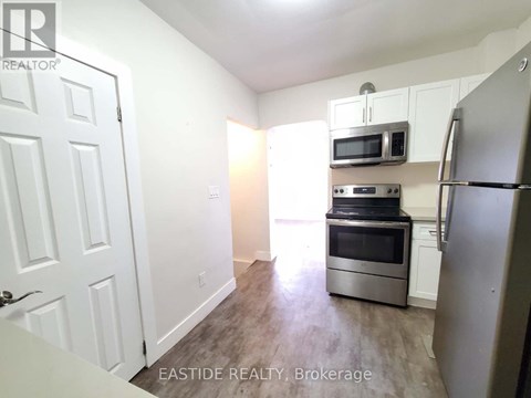 A kitchen with a refrigerator, microwave, and oven.