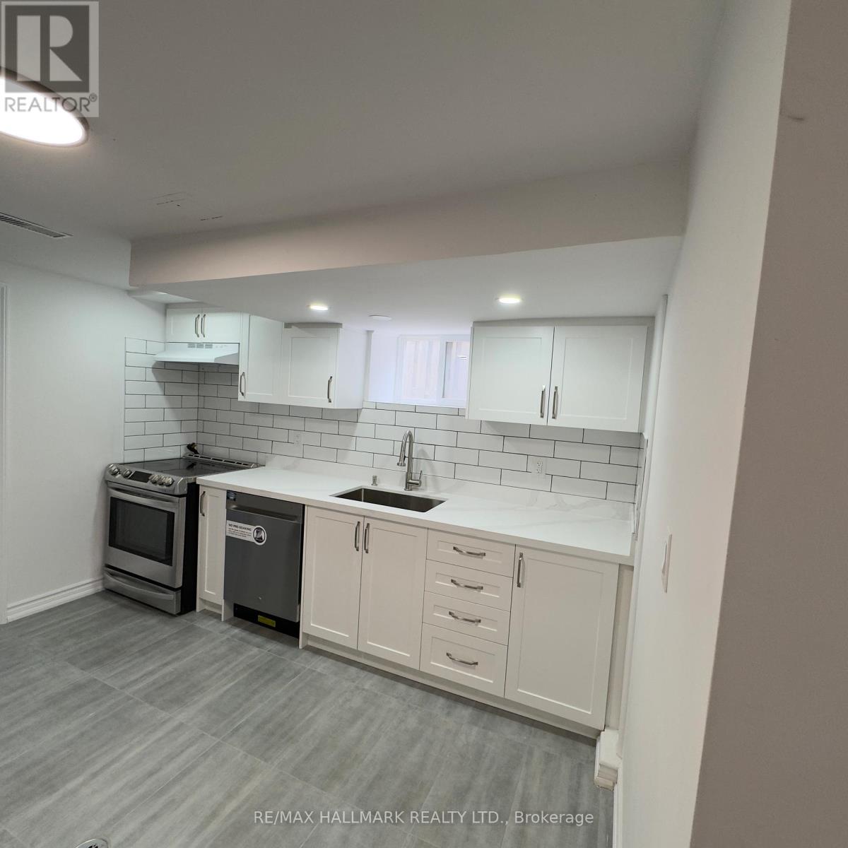 A kitchen with white cabinets and a grey floor.