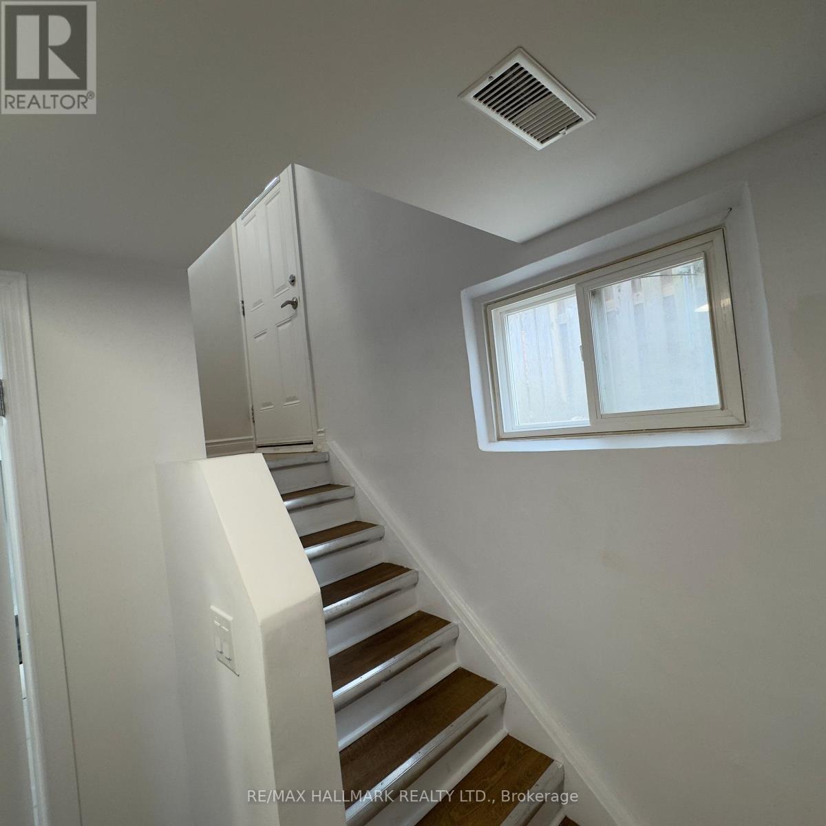 A staircase with a white wall and a window.