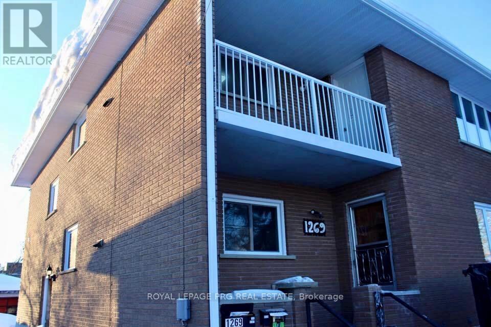 A two-story brick building with a balcony on the second floor.
