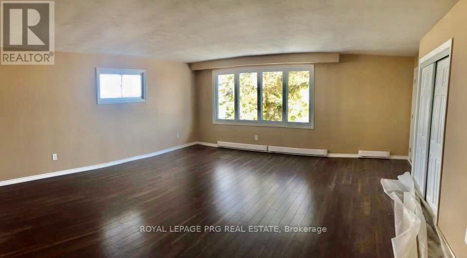A spacious room with wooden floors and a large window.