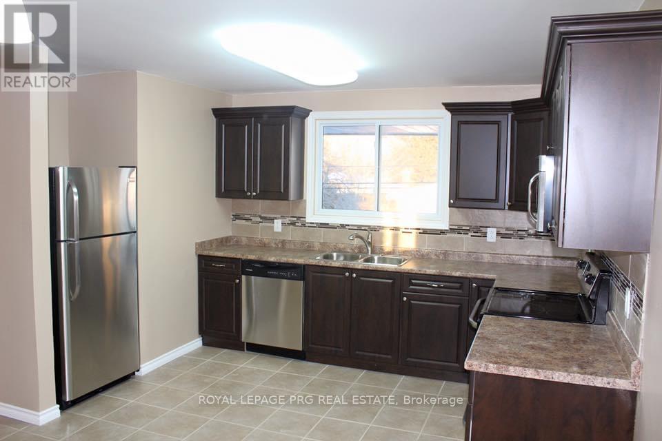 A kitchen with a refrigerator, sink, and cabinets.