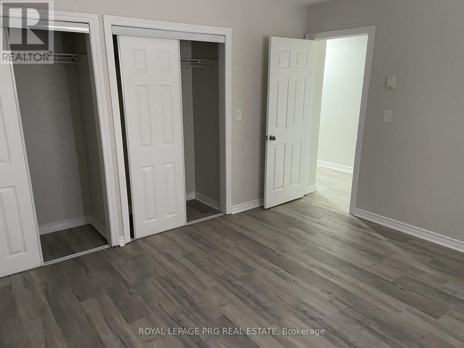 A room with three white doors and a grey floor.