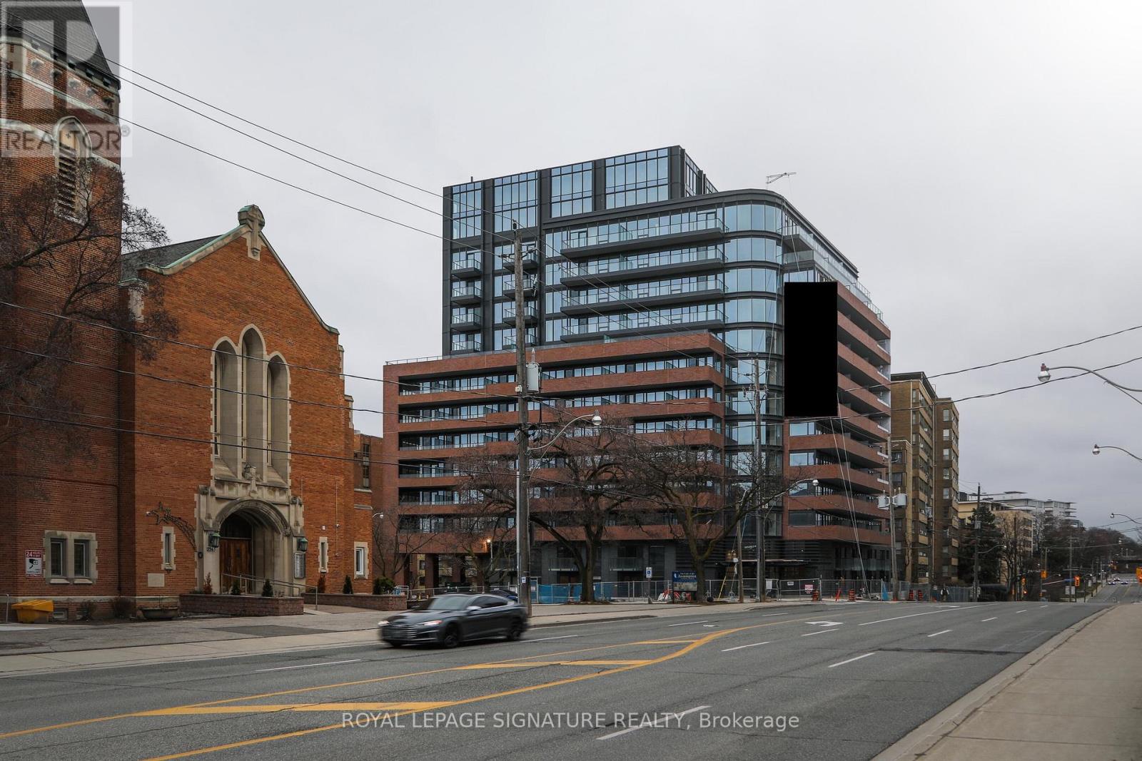 A car is driving down a street past a church and a large building.