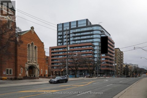 A car is driving down a street past a church and a large building.