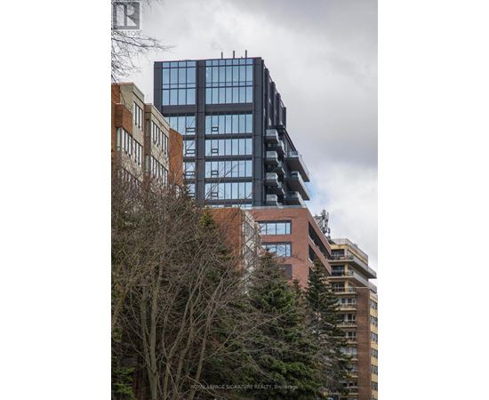 A tall building with many windows stands next to a shorter building with fewer windows.