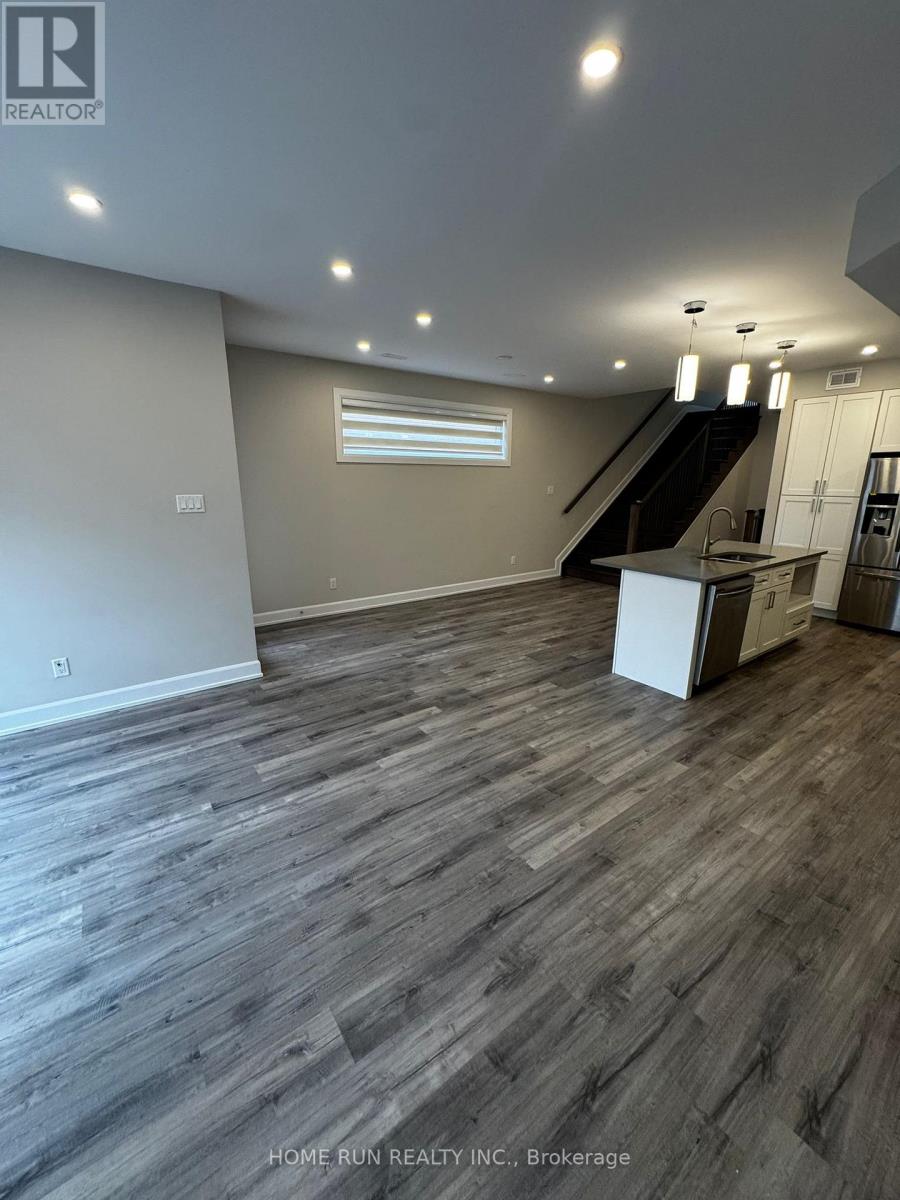A spacious room with wooden flooring and a staircase on the right side.