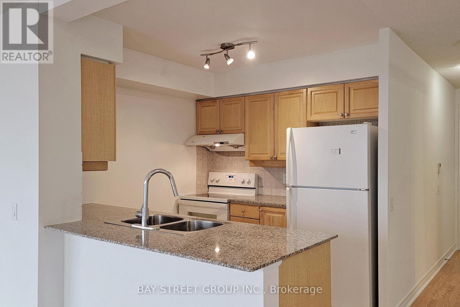 A kitchen with a sink, stove and refrigerator.