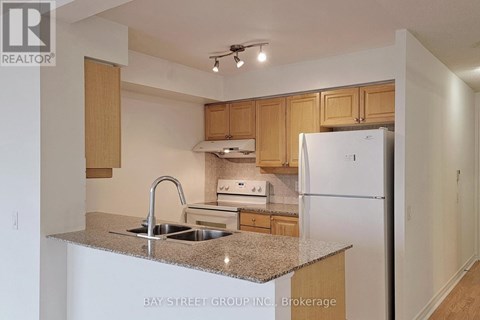 A kitchen with a sink, stove and refrigerator.