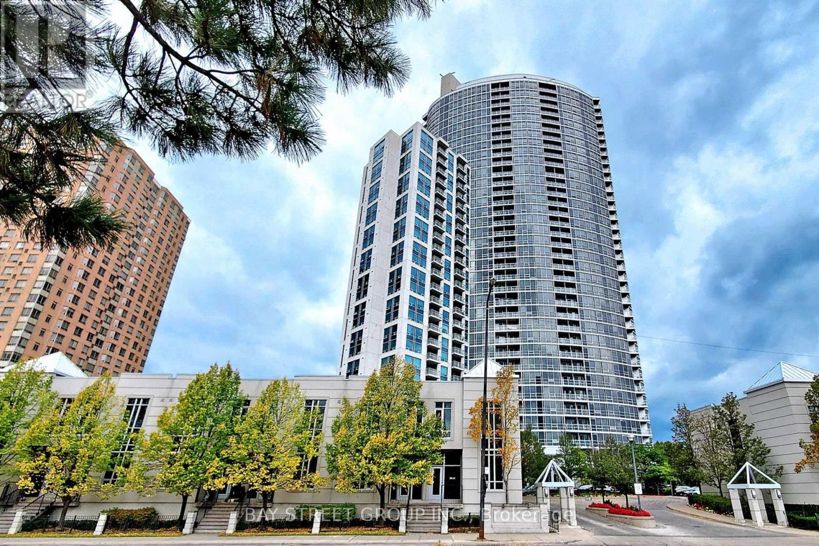 A modern glass building stands tall in the foreground of a cityscape.