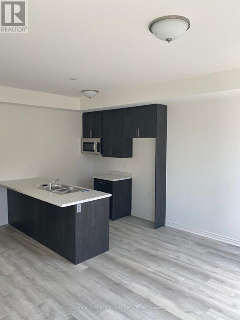 A kitchen with a sink, microwave, and cabinets.