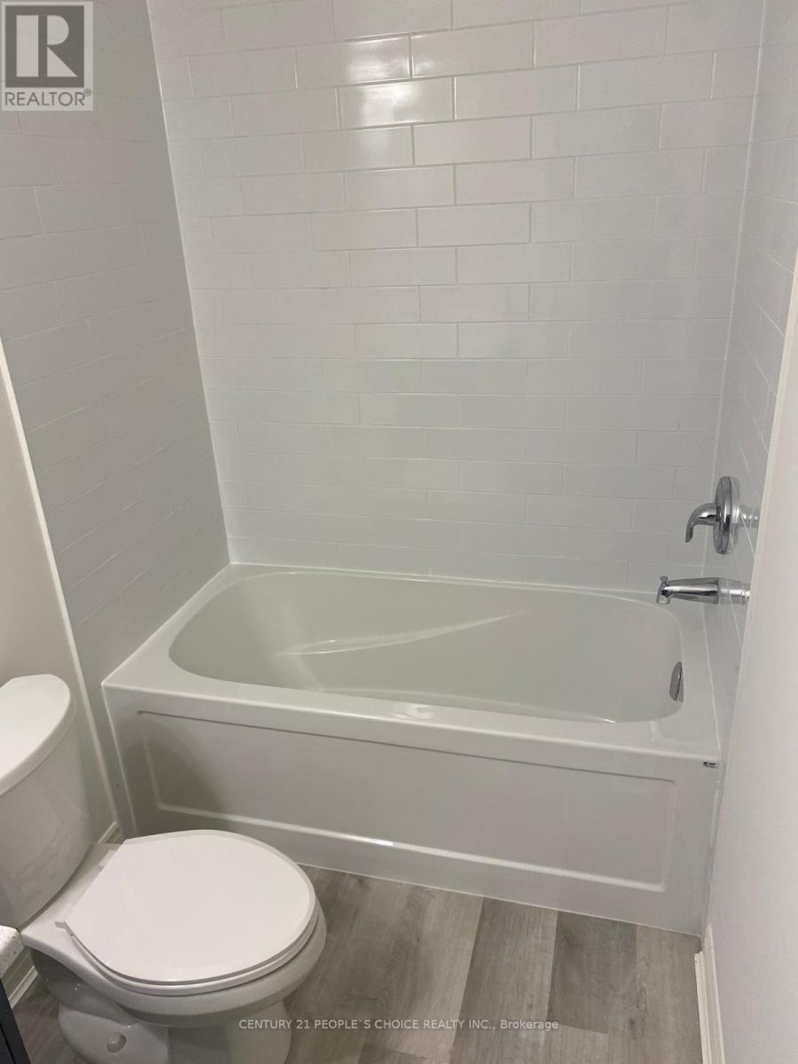 A white toilet sits next to a white bathtub in a bathroom.