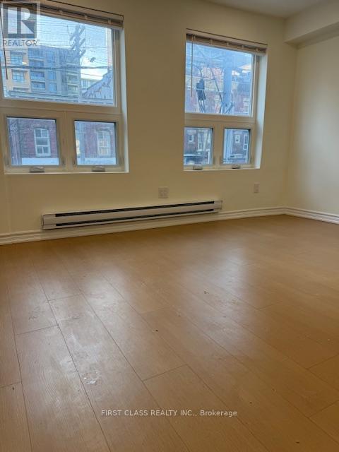 A room with wooden flooring and three windows.