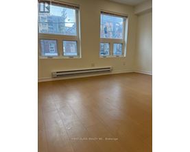 A room with wooden flooring and three windows.