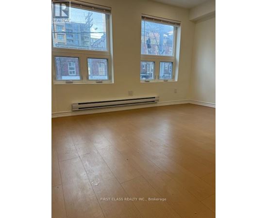 A room with wooden flooring and three windows.