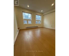 A room with wooden flooring and two windows.