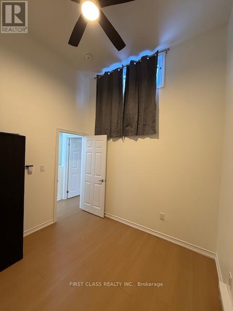 A room with a ceiling fan and a doorway leading to another room.
