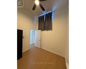 A room with a ceiling fan and a doorway leading to another room.