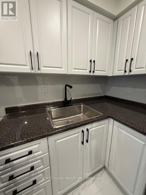 A kitchen with white cabinets and a granite countertop.