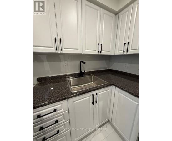 A kitchen with white cabinets and a granite countertop.