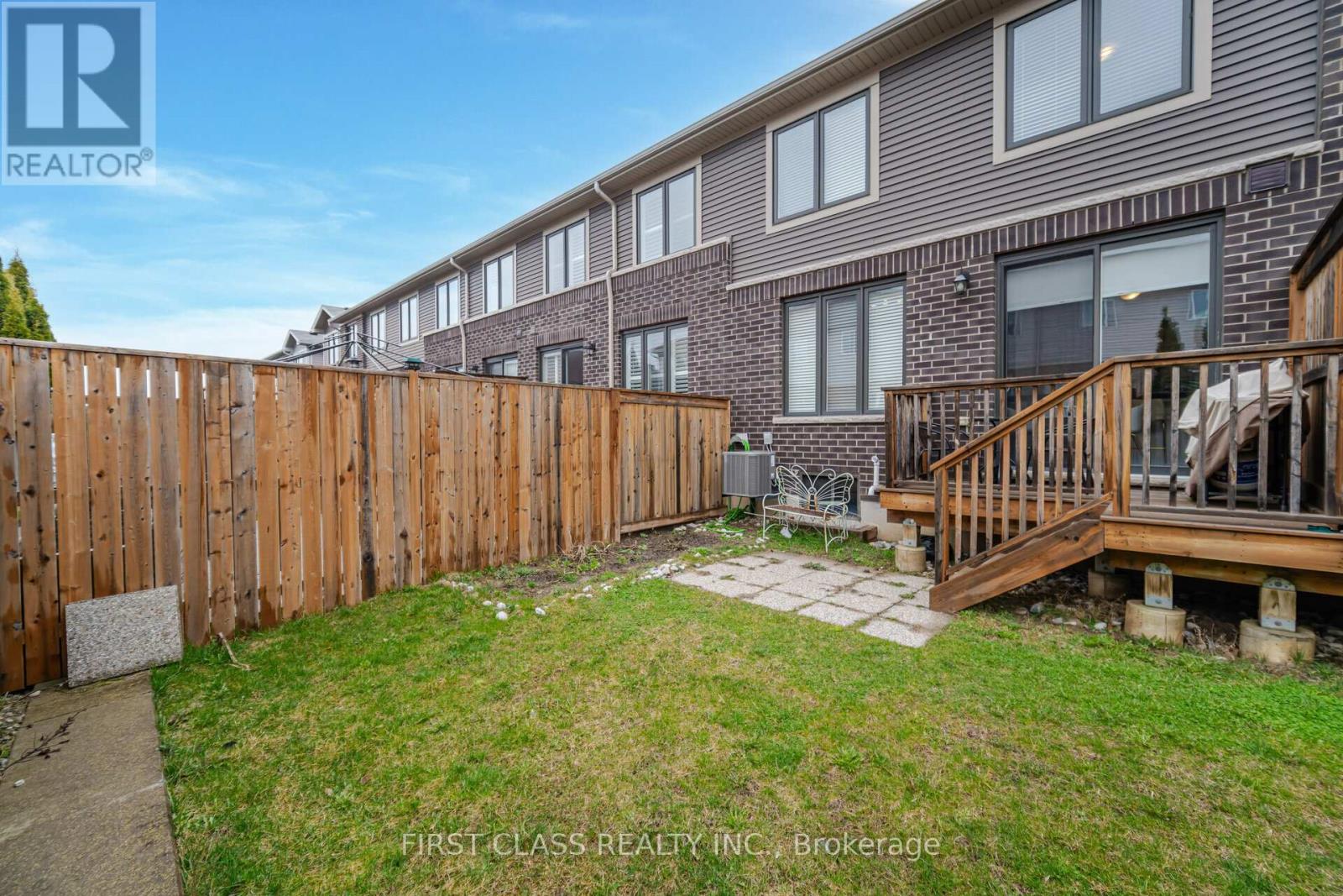 A wooden fence surrounds a grassy yard in front of a brick building.