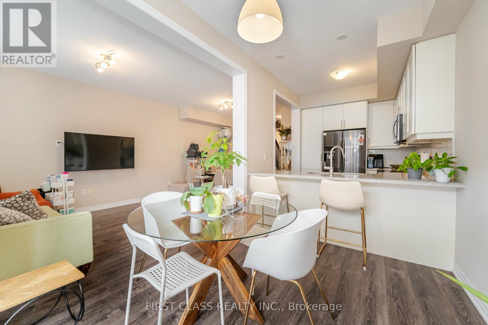 A modern dining room with a glass table and white chairs.