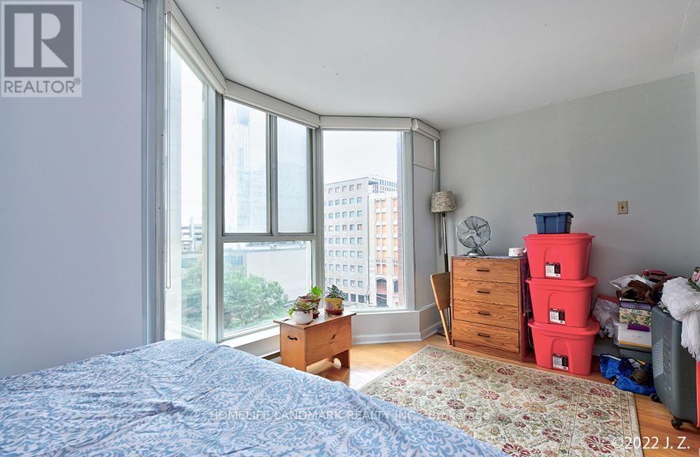 A bedroom with a large bed and a window overlooking a cityscape.