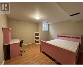 A bedroom with a pink bed and a desk with a chair.