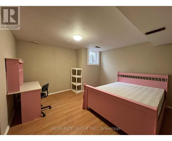 A bedroom with a pink bed and a desk with a chair.