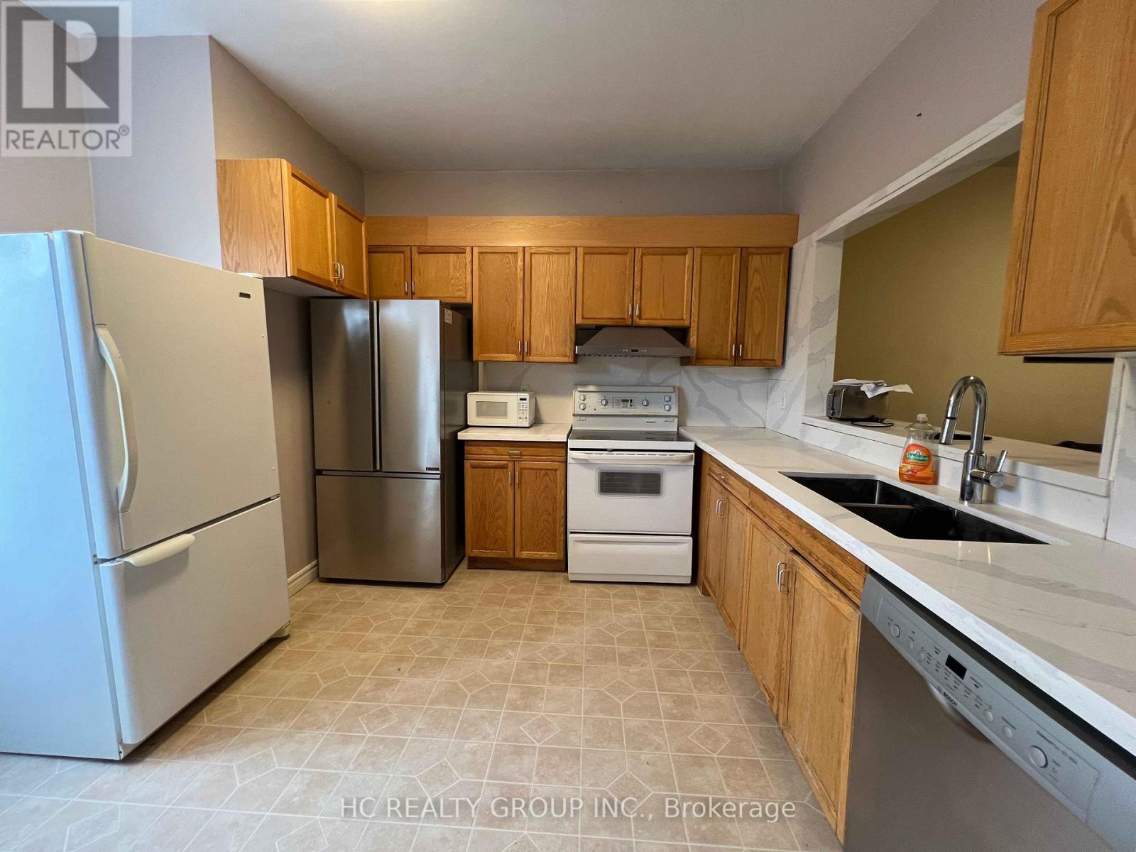 A kitchen with a refrigerator, microwave, oven, and sink.