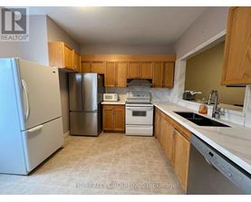 A kitchen with a refrigerator, microwave, oven, and sink.