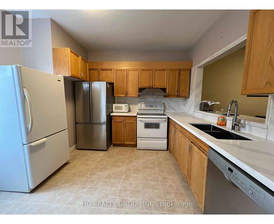 A kitchen with a refrigerator, microwave, oven, and sink.