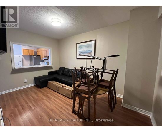 A living room with a black couch, a wooden dining table with chairs, and a cardboard box on the floor.