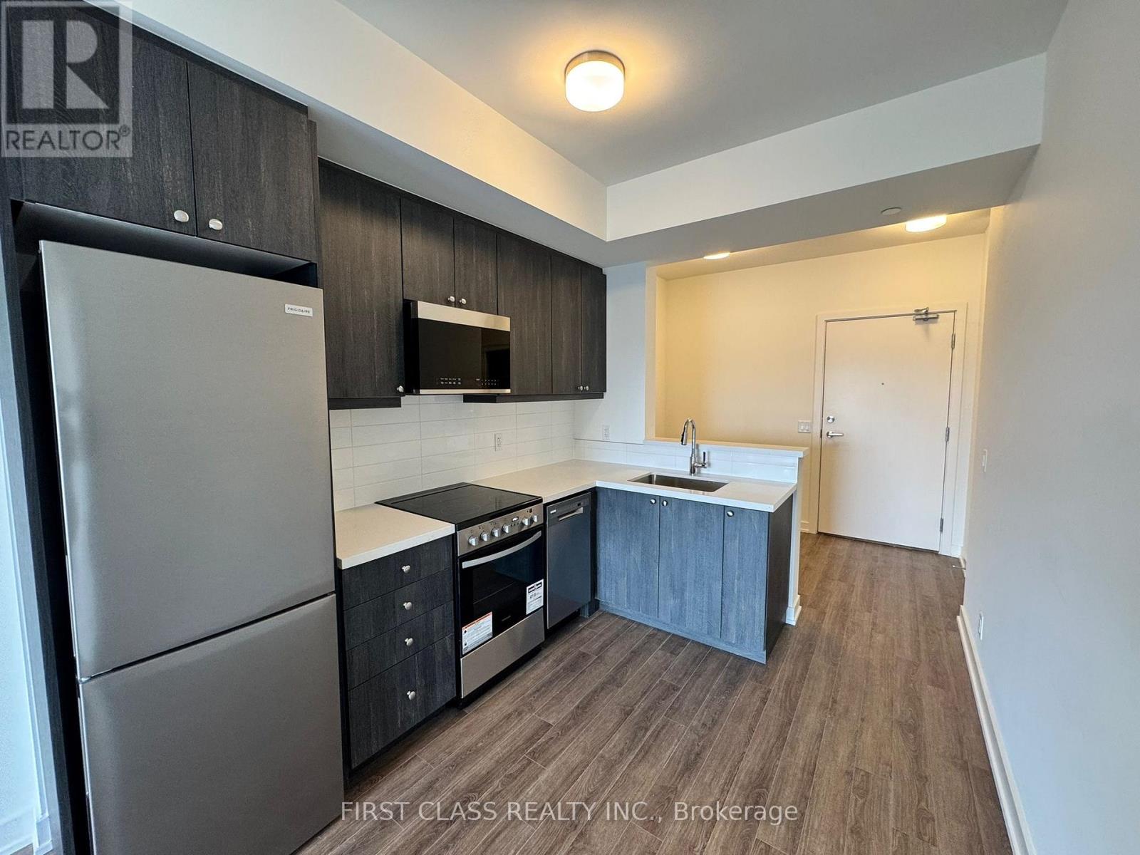 A kitchen with a refrigerator, sink, and cabinets.
