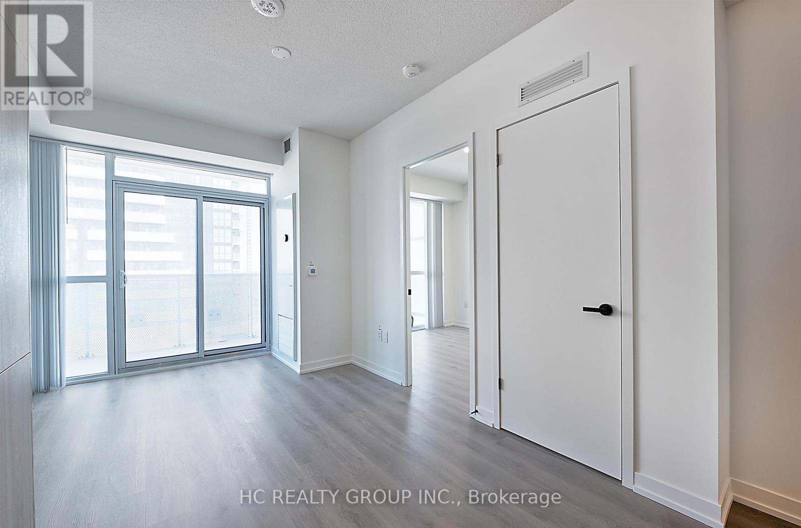 A spacious room with a sliding glass door and a white door.