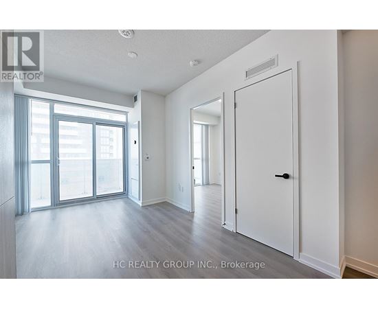 A spacious room with a sliding glass door and a white door.