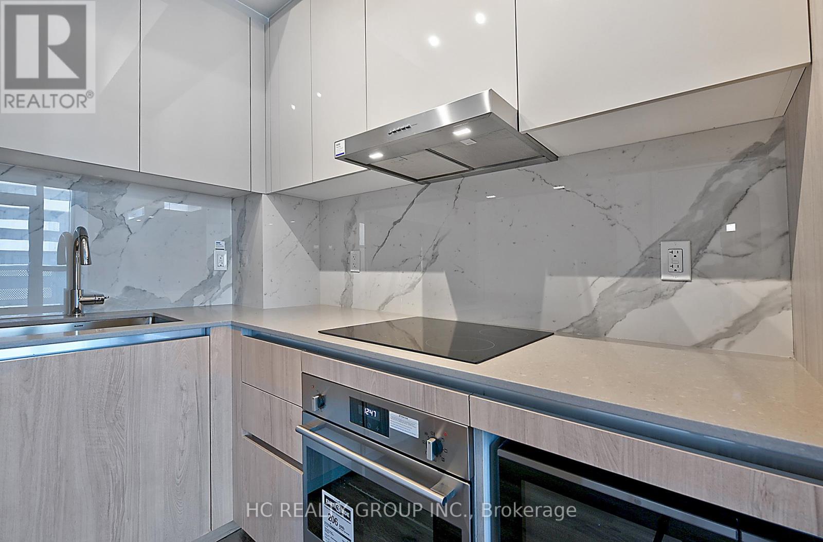 A modern kitchen with a stainless steel oven and a marble backsplash.
