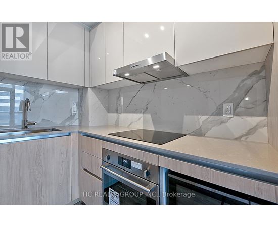 A modern kitchen with a stainless steel oven and a marble backsplash.