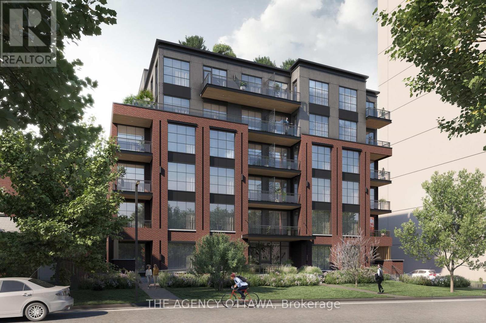 A modern apartment building with balconies and greenery on the roof.