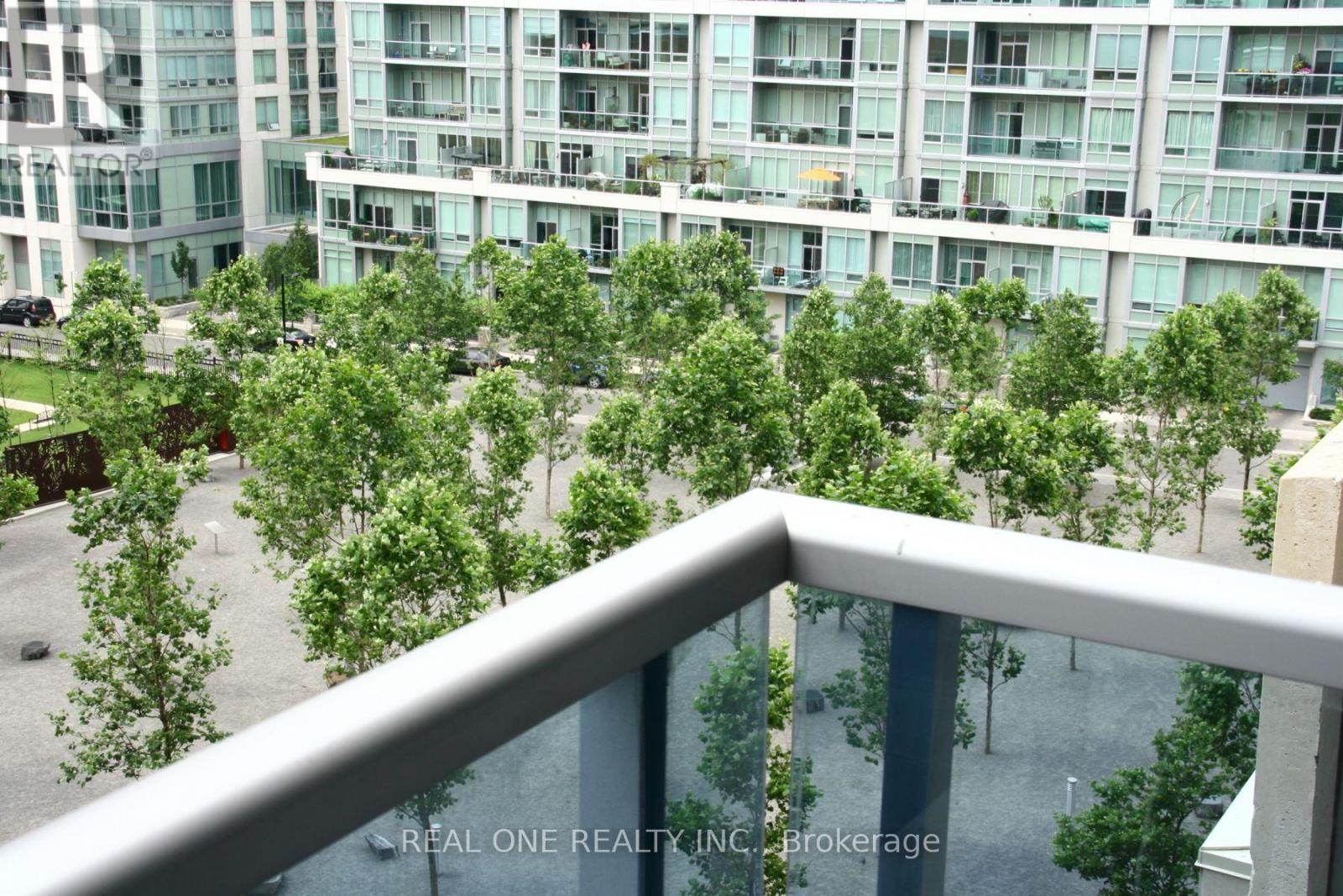A balcony overlooks a courtyard with trees and a building in the background.